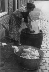 221137 Afbeelding van een vrouw die de was doet op straat, ter hoogte van het huis Kroonstraat 87 te Utrecht.